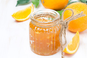 Fototapeta na wymiar orange jam in a glass jar and oranges on the table