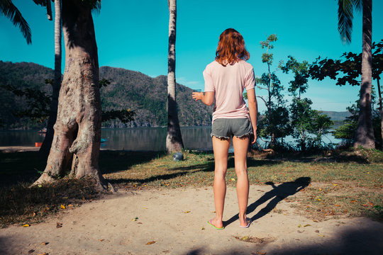 Young woman standing by palm trees