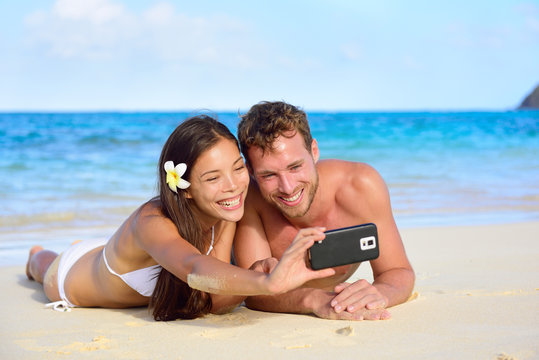 Beach holiday couple taking selfie with smartphone