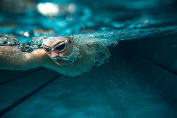 Fotobehang Mannelijke zwemmer bij het zwembad. Onderwater foto. © BalanceFormCreative