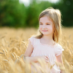 Fototapeta na wymiar Adorable girl walking happily in wheat field