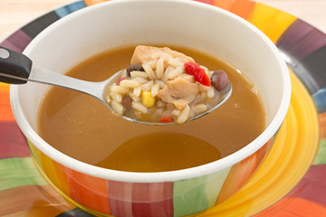Spoonful of chicken soup with bowl