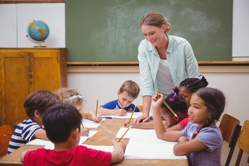 Teacher and pupils working at desk together