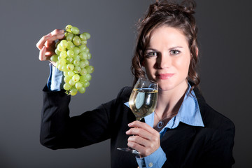 Frau mit Weißwein und Weintrauben in der Hand bei der Weinprobe Porträt