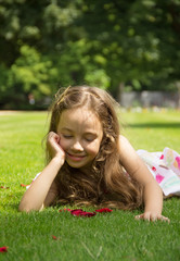 Pretty little girl resting on a green grass
