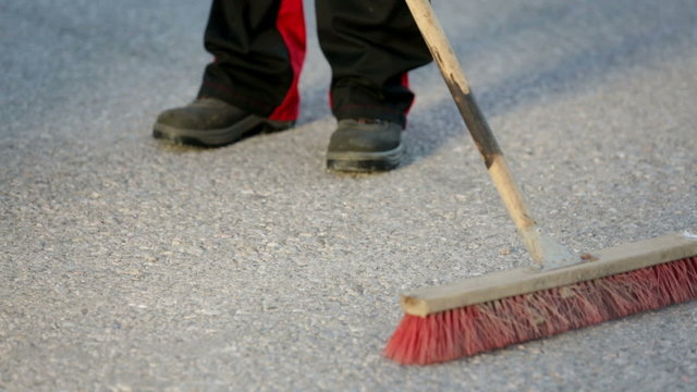 Worker sweeps the floor with a wide broom