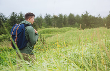 Naklejka na ściany i meble Hiker man walking among high grass in summer