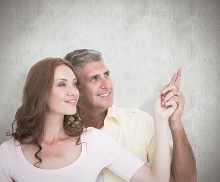 Composite image of casual couple smiling and pointing