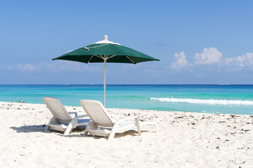 Pair of sun loungers and umbrella on a tropical beach in Cancun,