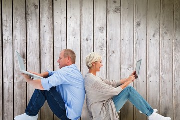 Composite image of mature couple using laptop and tablet pc