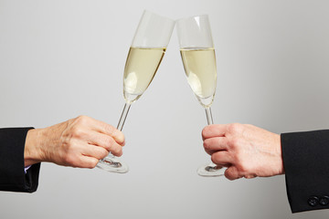 Zwei Hände stoßen mit Sekt im Glas an