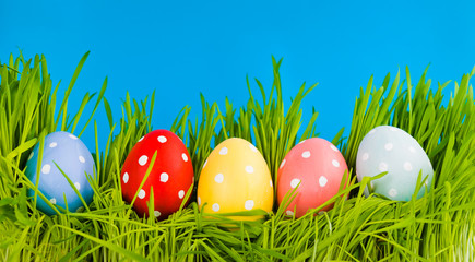 Colorful easter eggs in a row on green grass