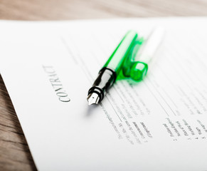 Pen and contract papers on wooden desk