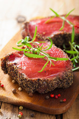 raw beef steak with spices and rosemary on wooden background
