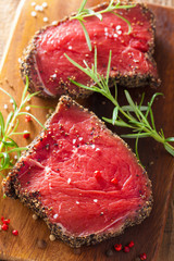 raw beef steak with spices and rosemary on wooden background