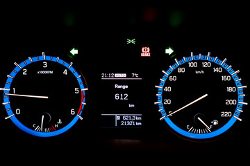 Backlit gauges of an automobile. Blue glowing meters with a whit