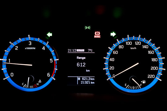 Backlit gauges of an automobile. Blue glowing meters with a whit
