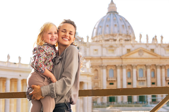 Portrait of happy mother and baby girl hugging in Vatican 