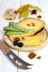 Cheese platter: solid cheese, olives, walnuts and autumn leaves