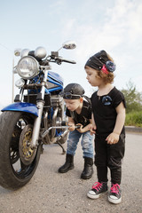 little biker repairs motorcycle on road