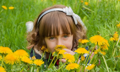 Portrait of  smiling child on  lawn with dandelions