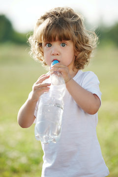 little girl drinking clean water from plastic bottle