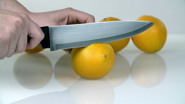 Cutting up the lemon with big kitchen knife in slow motion on white background