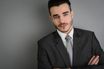 portrait of young business man posing in front of gray wall