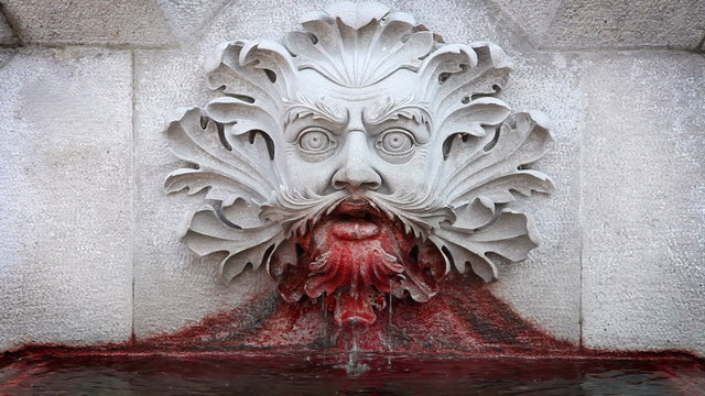 Close up of a statue of a man's head vomiting blood