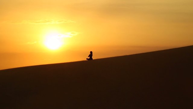 young girl practicing yoga in the desert at sunset