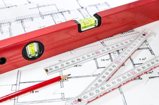 Wasserwaage, Stift und Zollstock auf einem Bauplan/Grundriss liegend 
