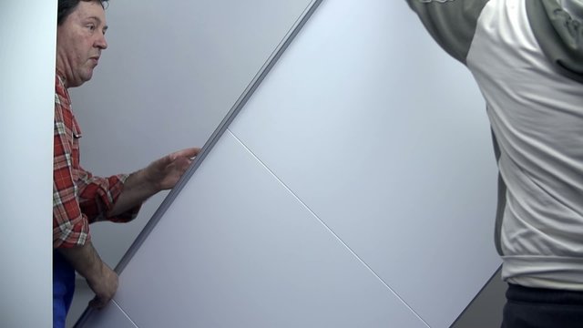 Two men lifting up the elements of the new furniture for the room