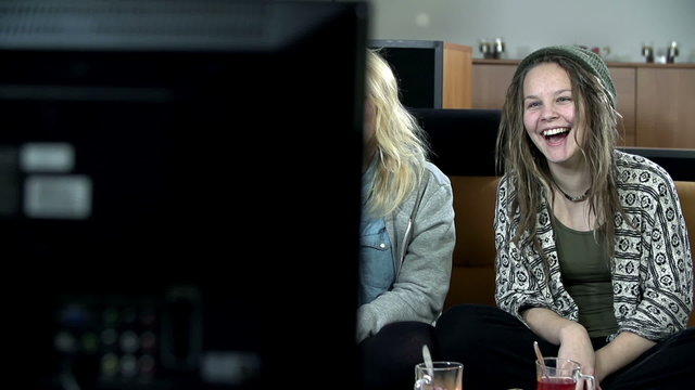 Girls look at television and smile mischievously
