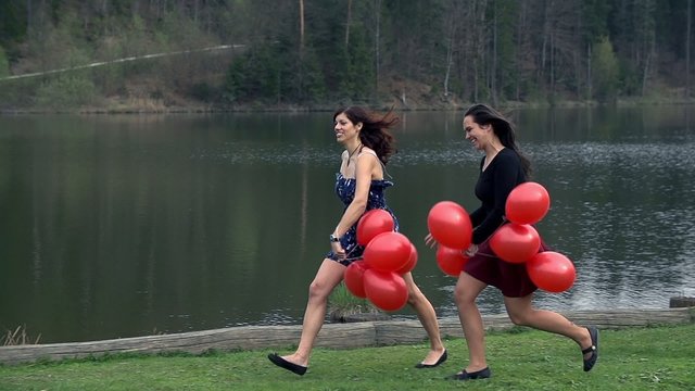 Two Young Ladies Enjoying Life At Lake With Red Balloons In Slow Motion