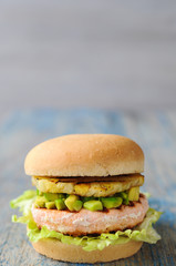 Homemade fish burger with salmon, avocado and pineapple.Close up