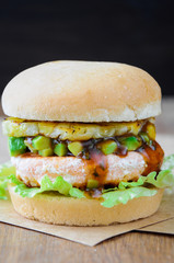 Homemade fish burger with salmon, avocado and pineapple.Close up