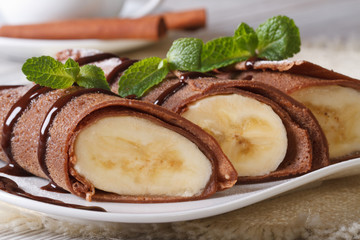 Chocolate pancakes with banana filling close-up horizontal