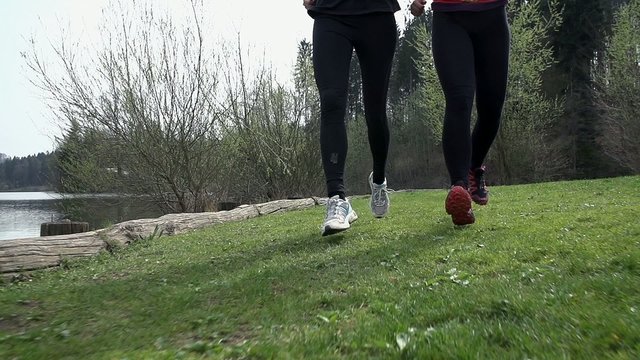 Slow Motion Close Up On Legs Running On Grass Beside Lake