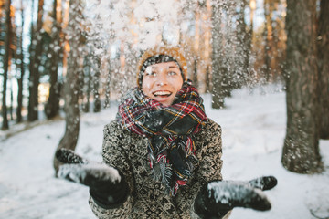Young woman  with snow in hands in winter forest