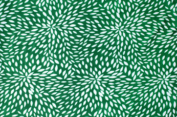 Abstract white floral pattern on green fabric as background.