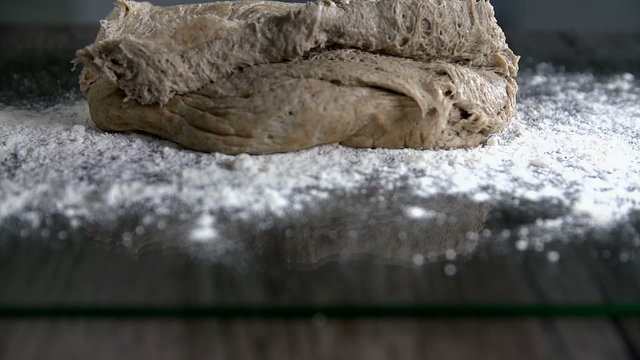 Dough falls onto the floured table  in slow motion