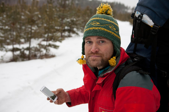 man with phone and map in hands traveling winter forest
