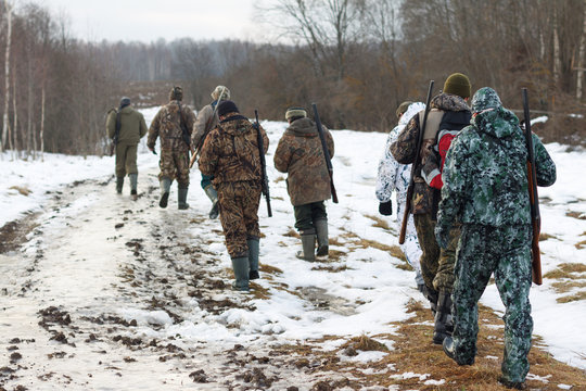 Group of hunters walking on the field in winter