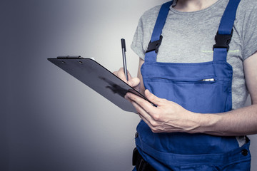 Arbeiter im Blaumann mit Klemmbrett