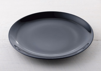 Empty black plate on wooden table