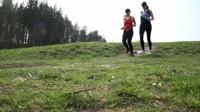 Slow Motion Landscape Shoot of Two Girls Running Down The Hill