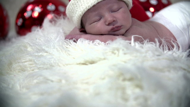 Tilt shot of baby sleeping ina Christmas scene laying on white furry blanket