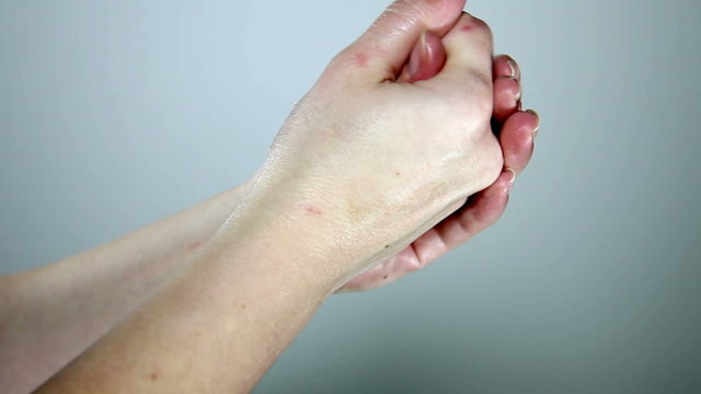 Close up shot of a woman`s hands spreading a cream ower the fingers