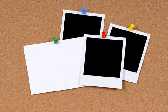 Several blank polaroid style photo prints with index card pinned to cork notice board
