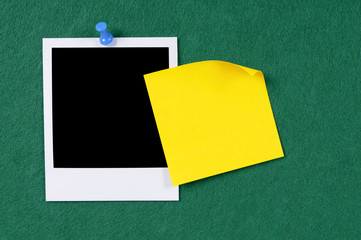 Blank polaroid style photo print frame with yellow sticky post it note on green felt bulletin board